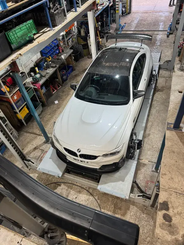 White BMW seen from above on a workshop ramp