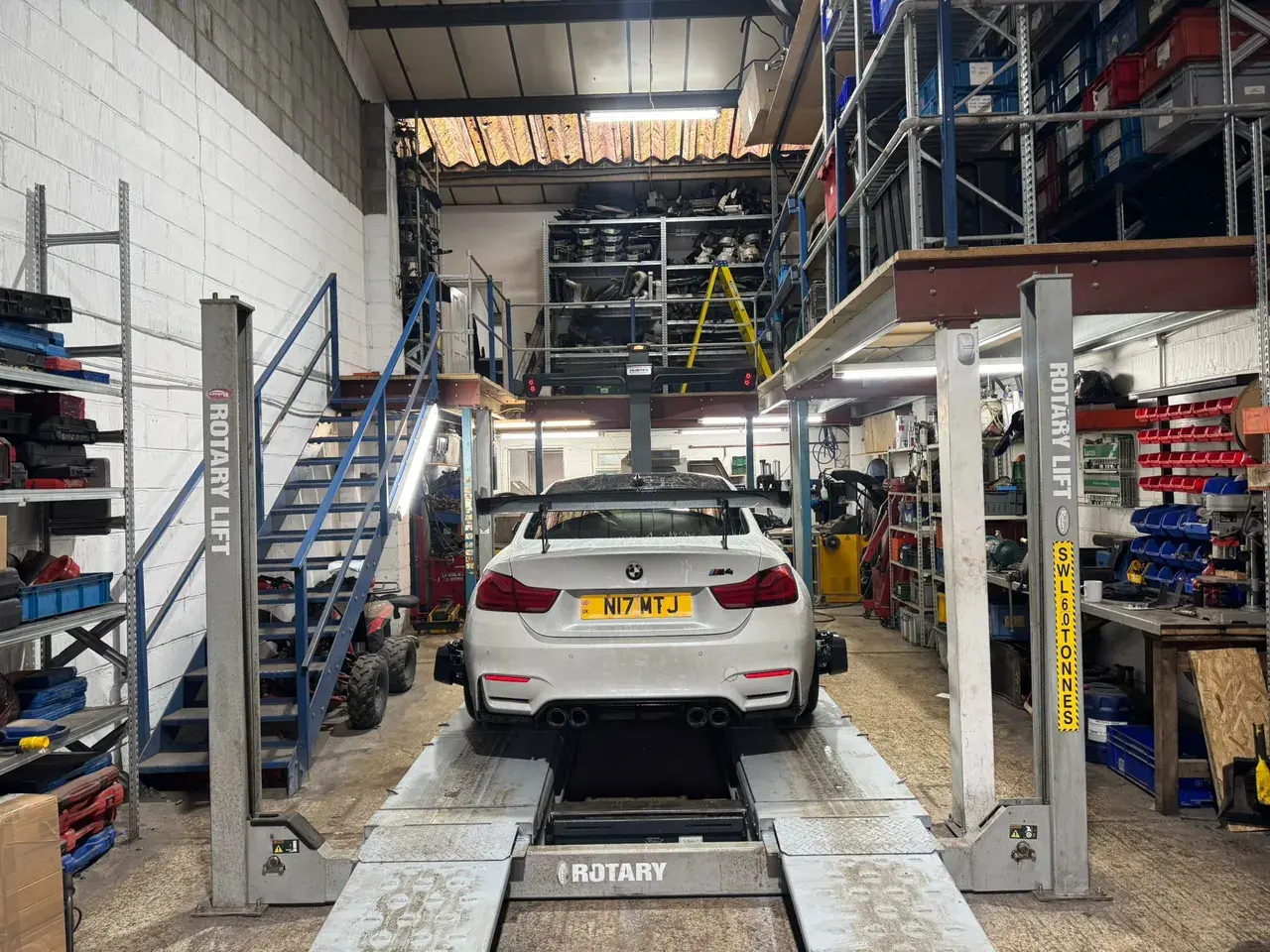White BMW M4 on the Hunter wheel alignment ramp, back view