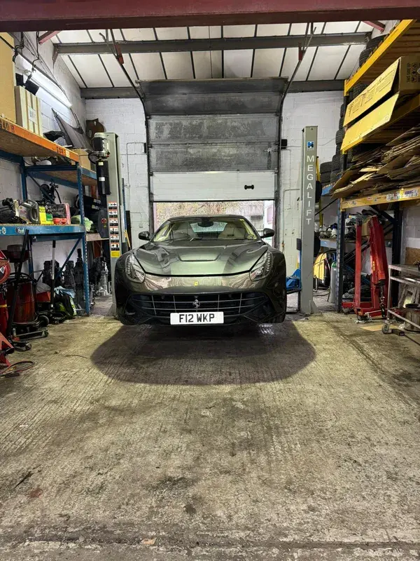 Grey Ferrari on a car lift for a service, front view